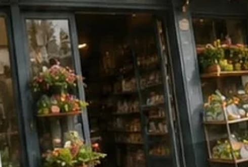 Fachada de un almacén de barrio con flores en la vitrina